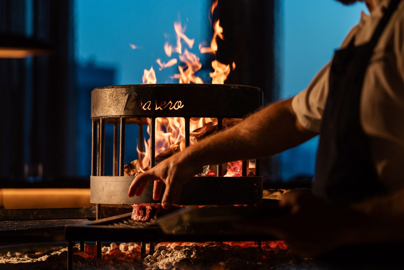 Brasero Atlántico Bahrain: Chef tending the coals of the live fire grill